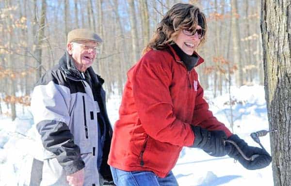 Cheryl Peterson drills the tree as Albert Martin looks on during last week's ceremony.[Elena Maystruk / The Observer]
