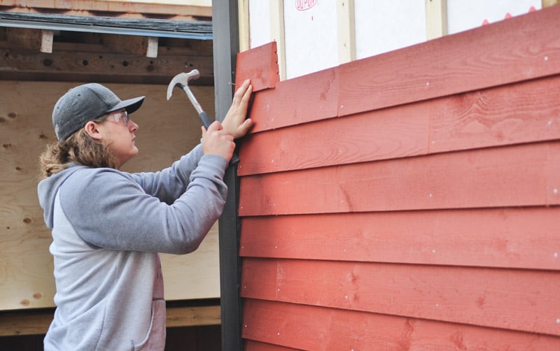 Adam Weber nails in some siding.[Whitney Neilson / The Observer]