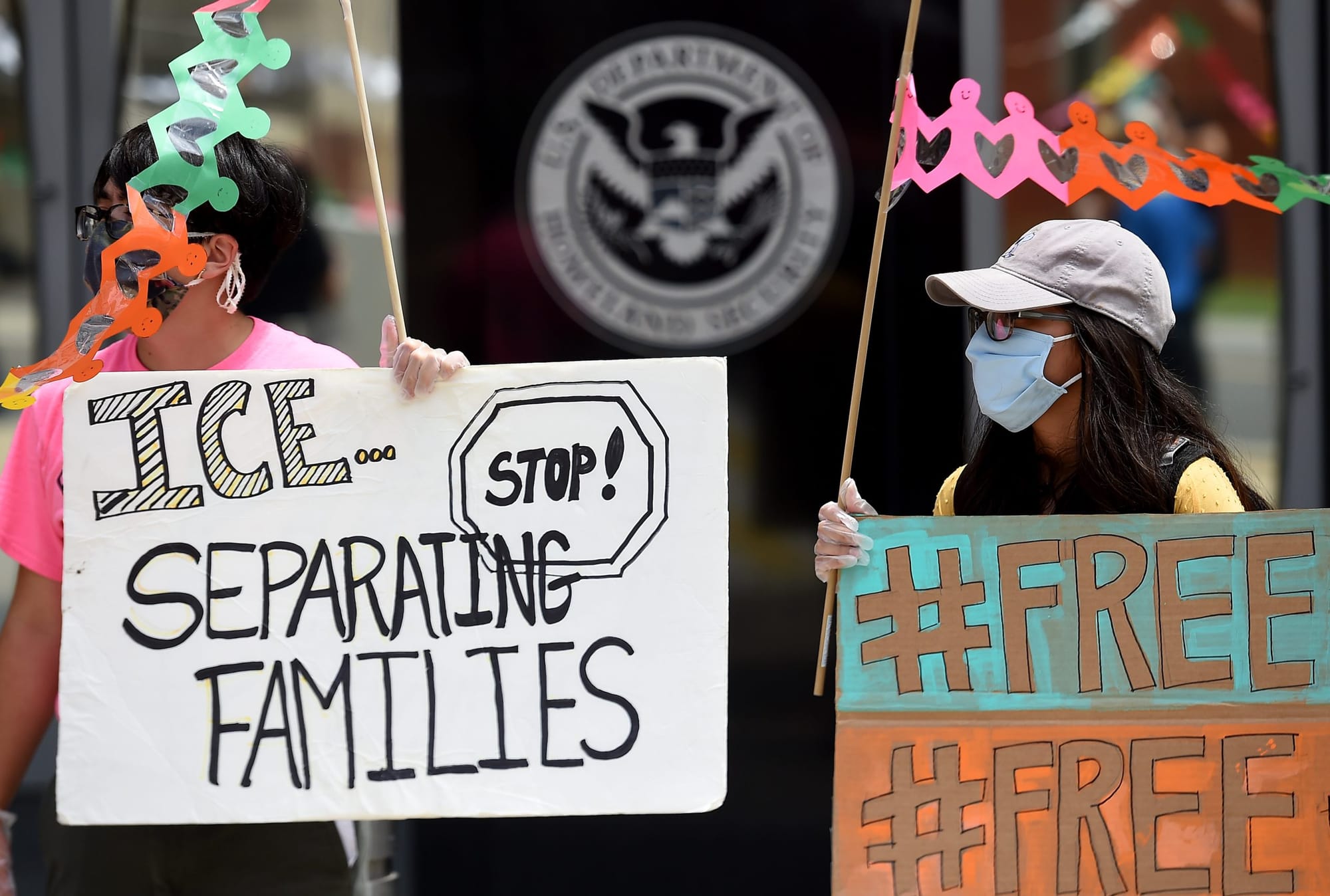people protest Immigration and Customs Enforcement with signs saying "ICE Stop separating families" and "#FREE"
