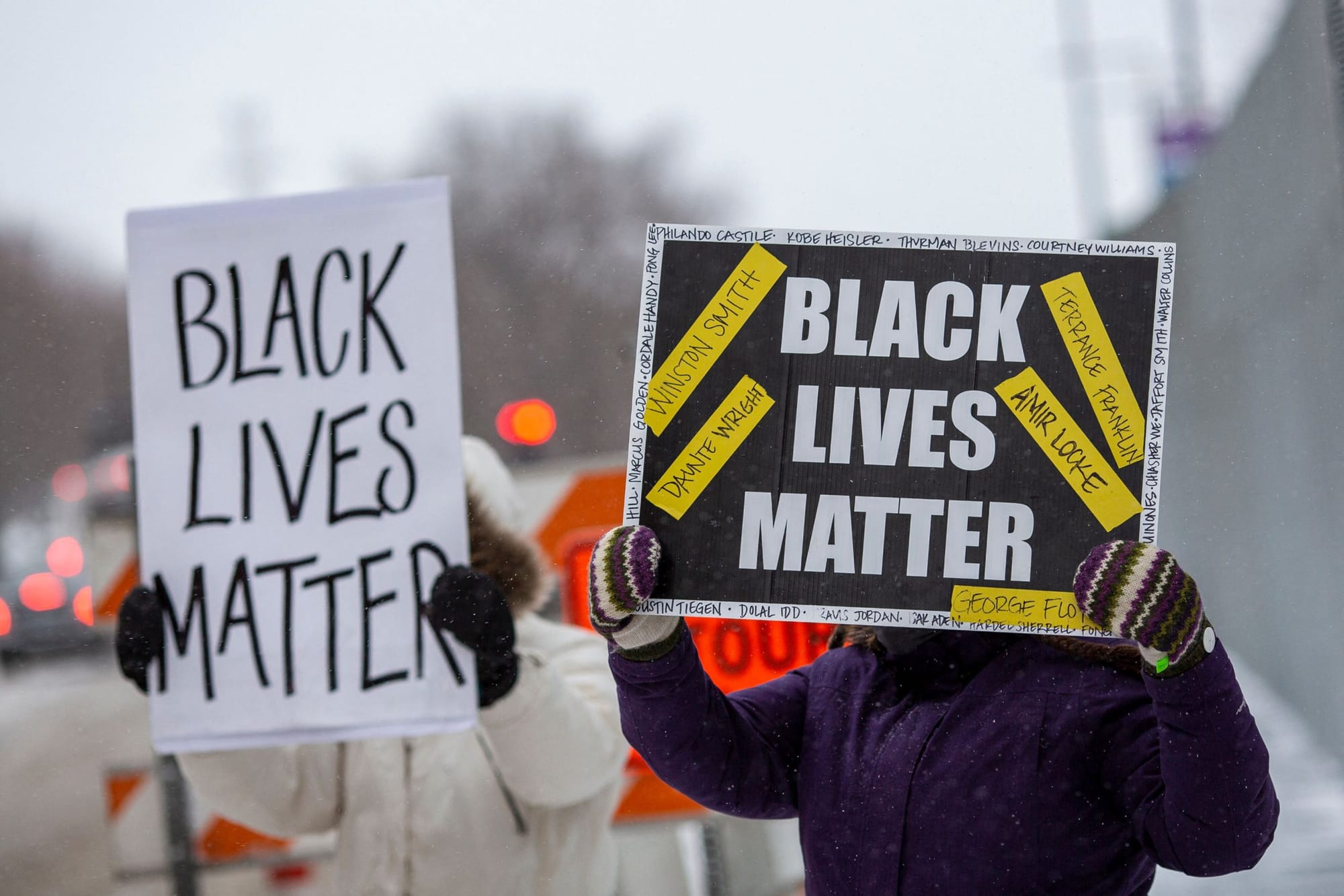 two people hold up signs saying "Black Lives Matter"