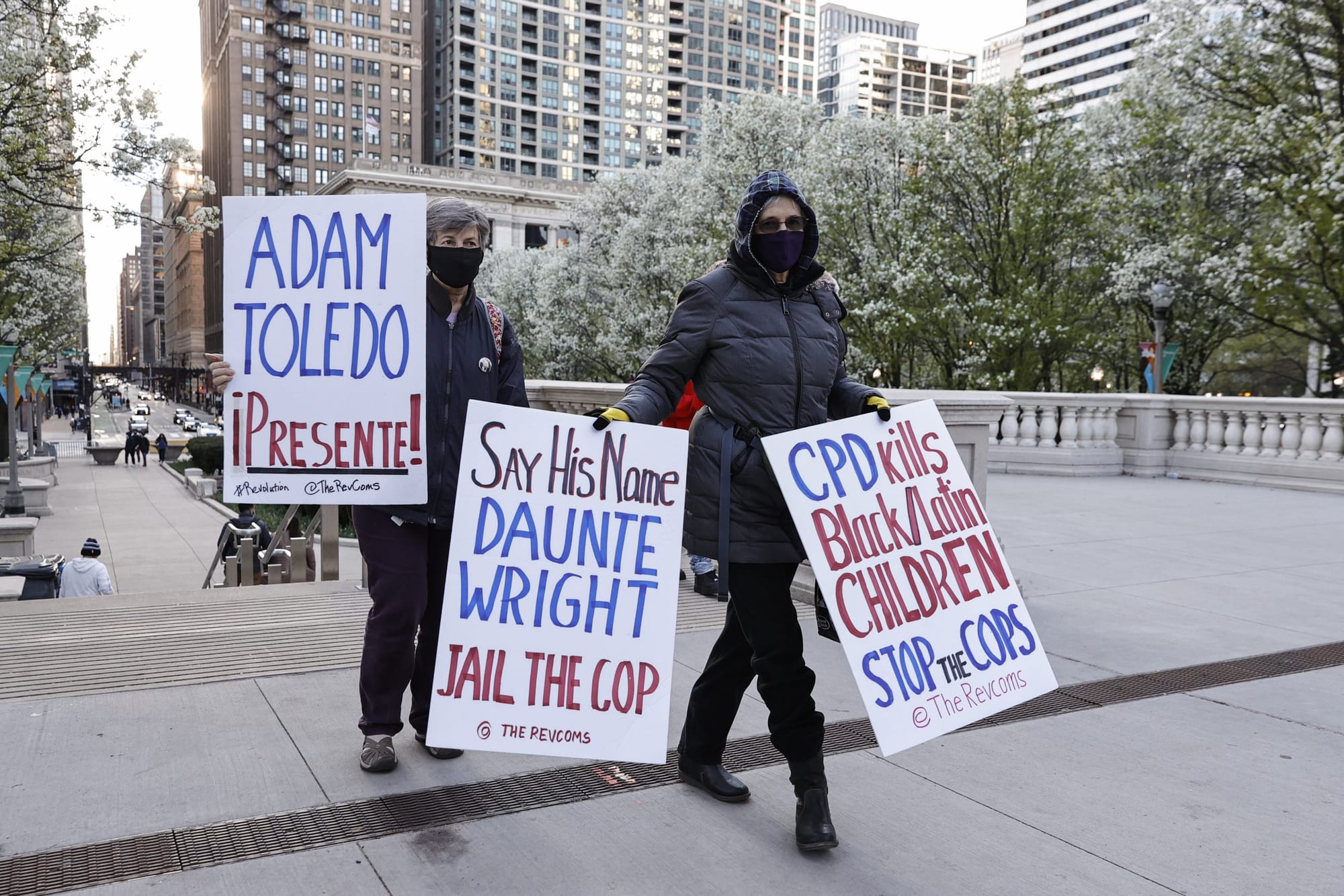 people stand in Millennium Park in Chicago holding signs protesting police violence against Daunte Wright and Adam Toledo