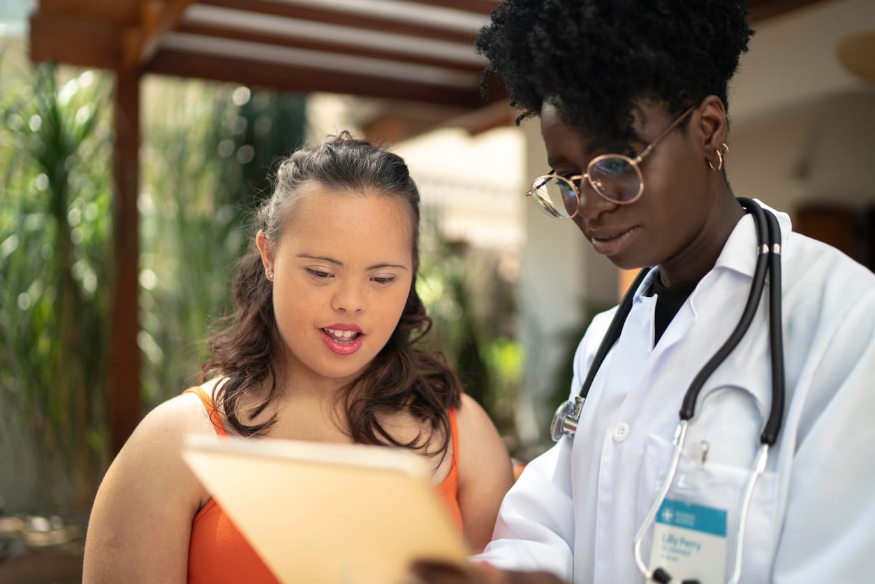Black home caregiver showing exam results to a special needs woman