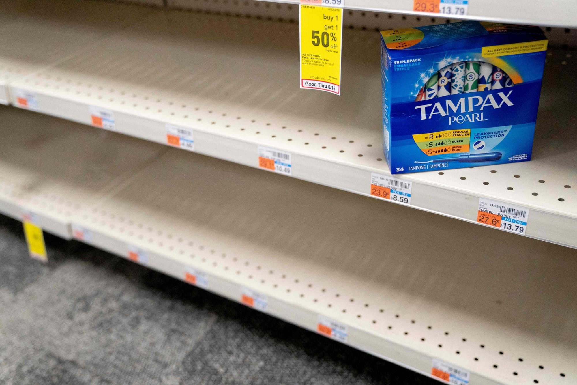 a box of Tampax pearl tampons in a blue cardboard box sits on an empty shelf