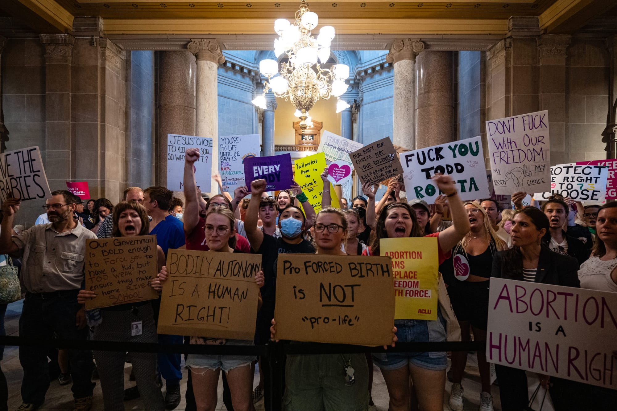 pro-choice protesters hold cardboard signs and posters with pro-arbortion messages
