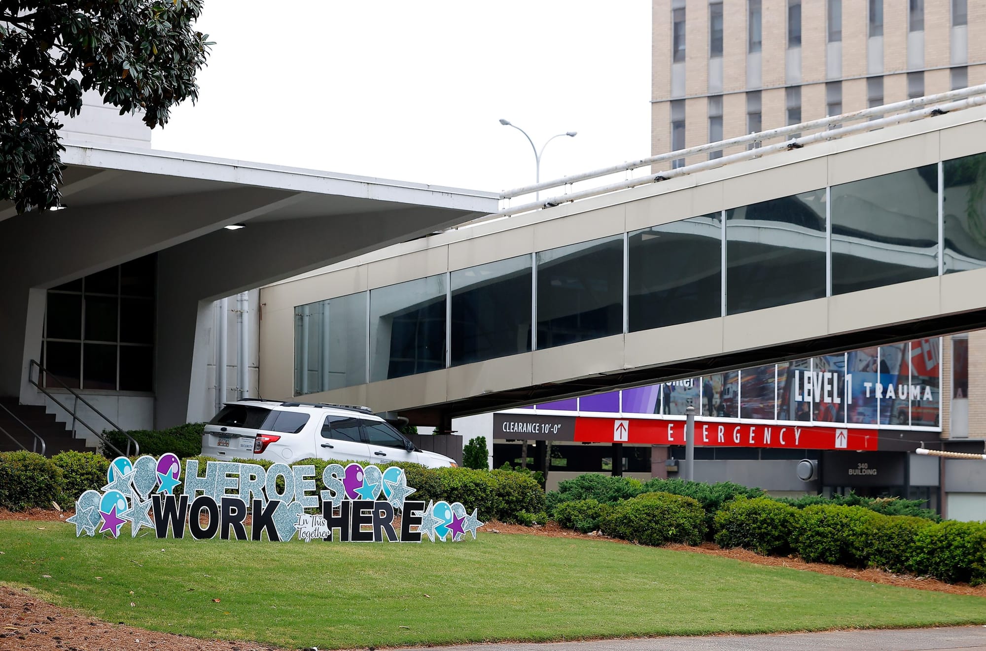 a large sign with cut-out blue and black letters reads "Heroes work here" on a green lawn in front of Atlanta Medical Center