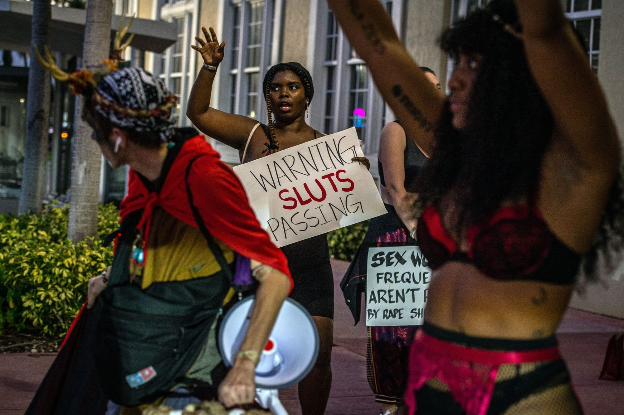 sex workers wearing colorful outfits hold signs in support of sex workers, including "warning sluts passing"