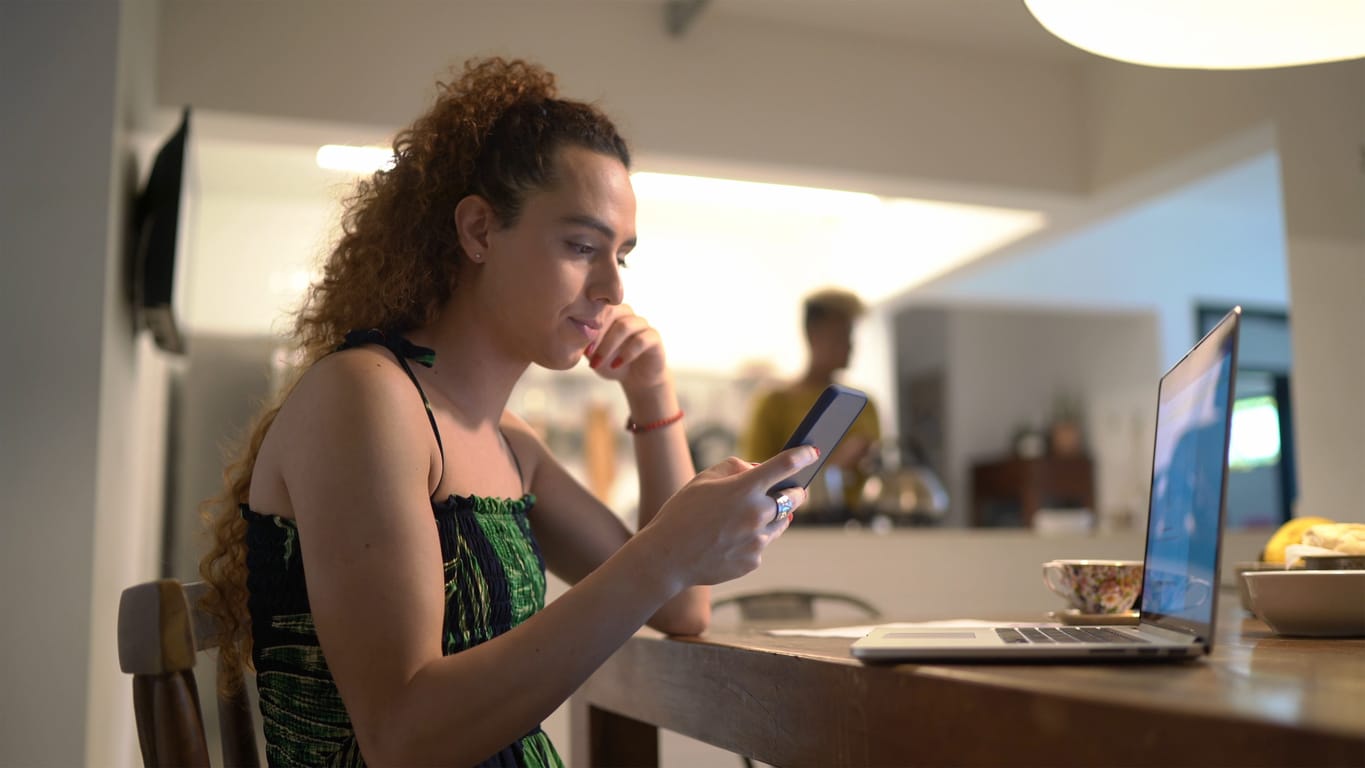 Transgender woman working and using smartphone at home