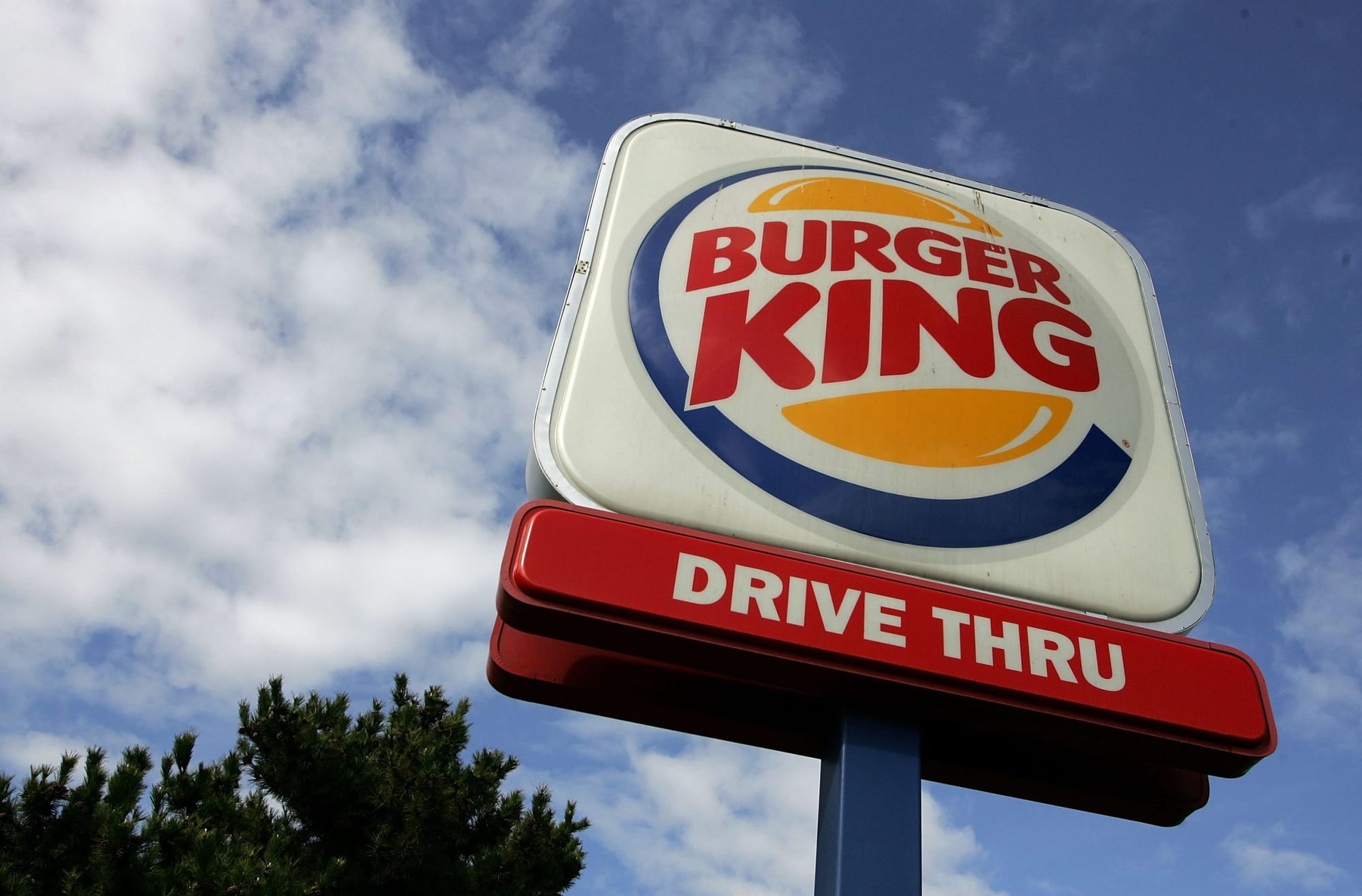 color photograph of a burger king sign against a cloudy blue sky