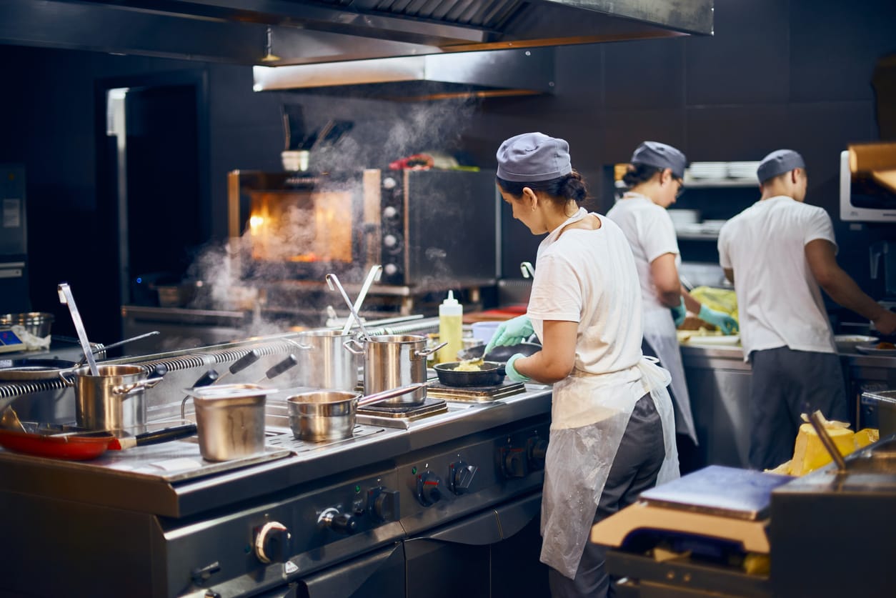color stock photo of a team of cooks facing away from the camera at work in a restaurant kitchen