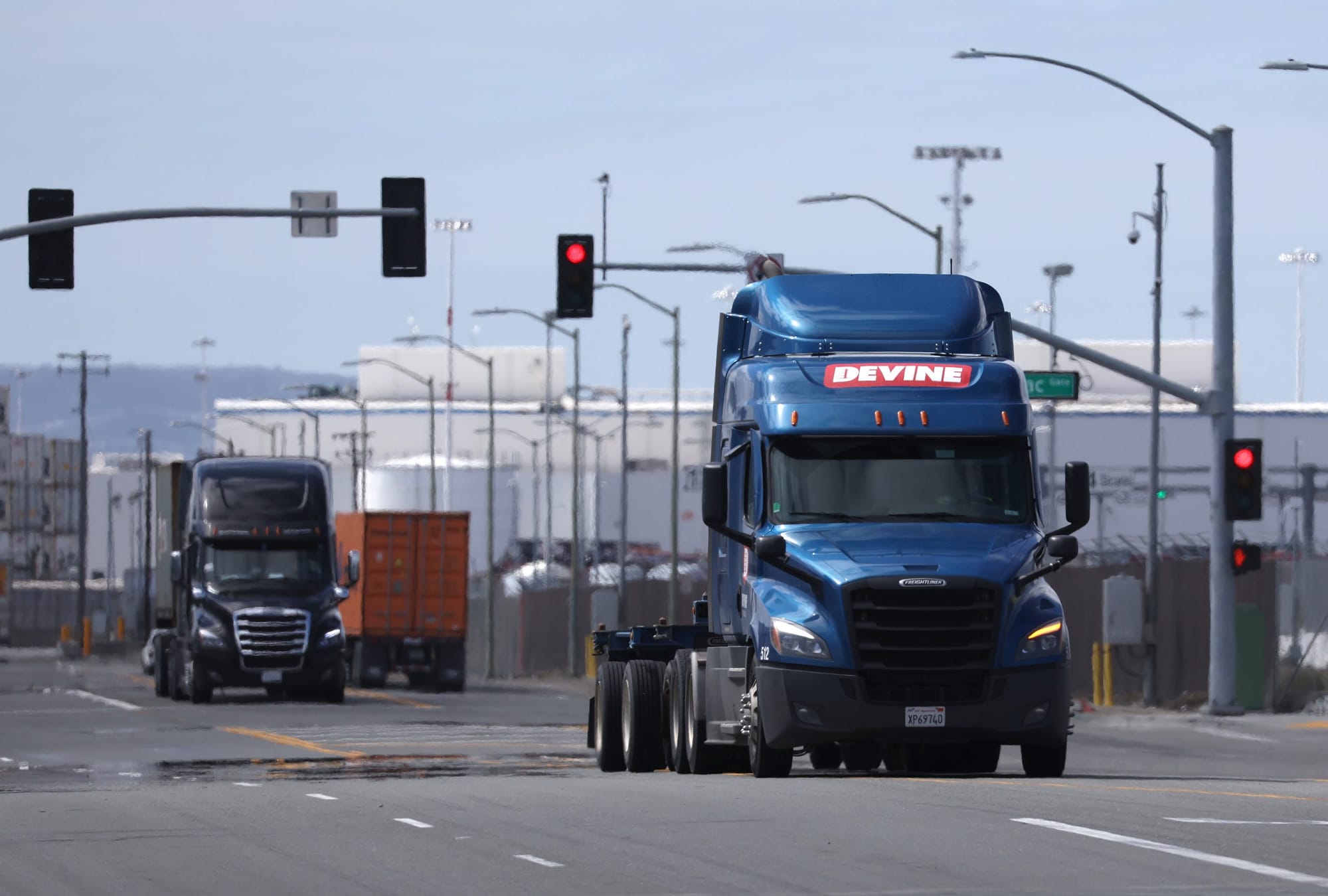 color photograph of a blue diesel truck driving towards the camera near an industrial facility