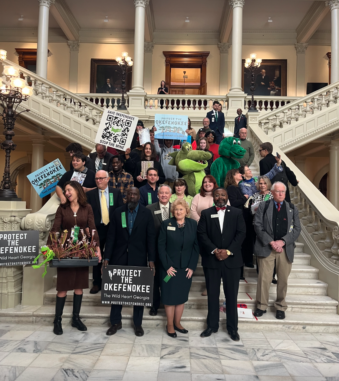color photographs of about two dozen people standing on the interior steps of a government building. they hold signs in support of protecting the Okefenokee Swamp