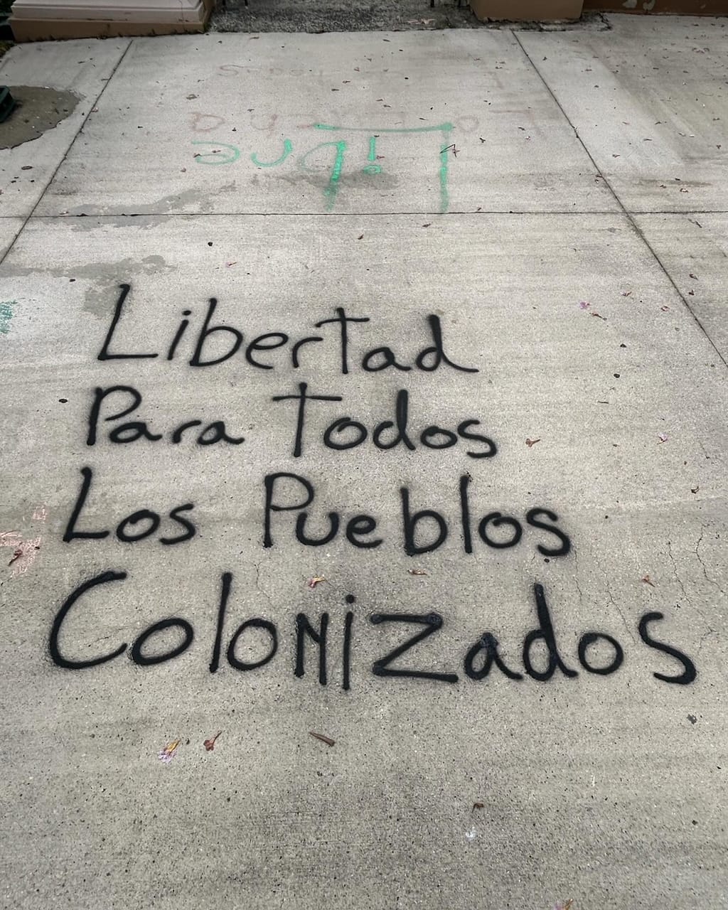 color photograph of spray paint on a sidewalk that reads "libertad para todos los pueblos colonizados"