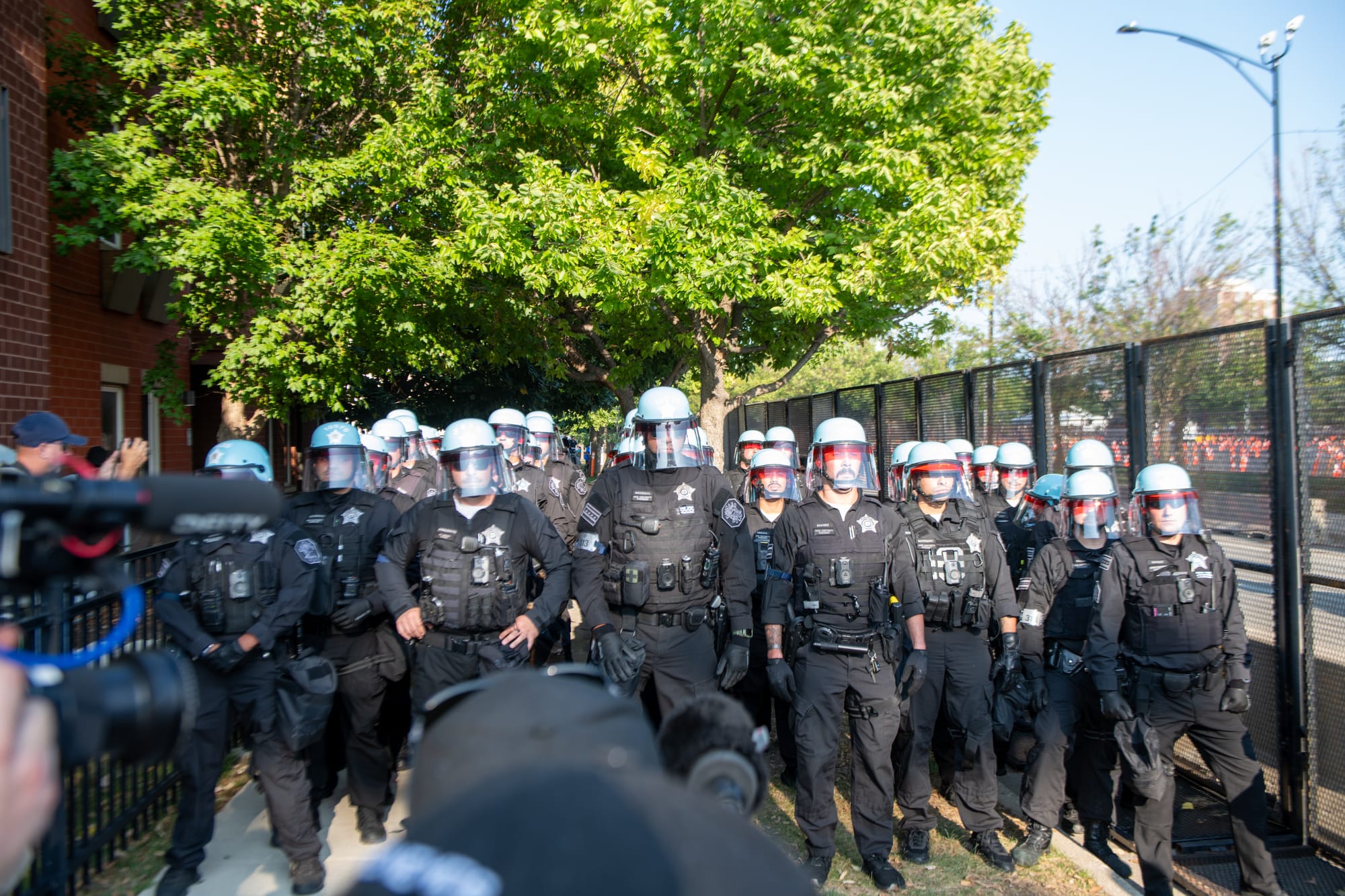 color photograph of police standing in rows of eight. at least three rows are visible stretching away from the camera on the street