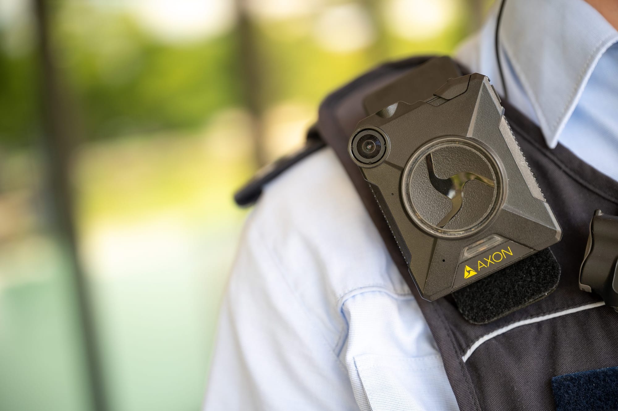A photo show a close-up of a uniformed officer’s shoulder with a black Axon body-worn camera.