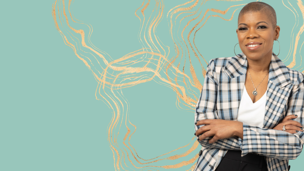 a Black femme person with a shaved head stands with their arms crossed in front of their torso. They are wearing and white an