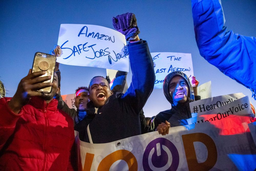 color photograph of an outdoor protest where Somali workers raise their fists and hold signs in support of workers rights. Si
