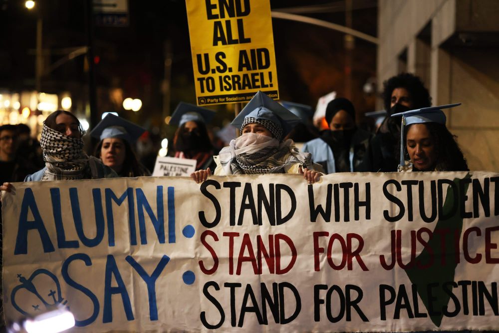 color photograph of an outdoor, nighttime protest by Columbia University alumni in support of Palestinian liberation. several