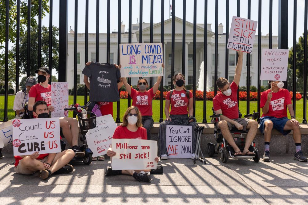 color photograph of protesters wearing red shirts and holding signs calling for data tracking, prevention, and treatment of l