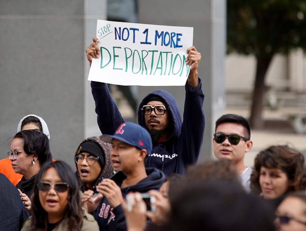 Protester holds sign that reads, "Stop. Not 1 more deportation."