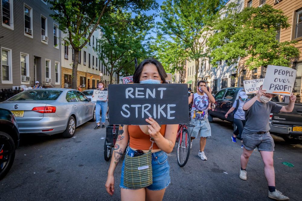 protester holding up sign that says "rent strike"