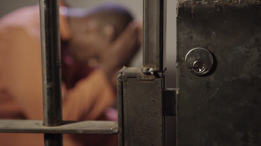 african-man-in-jail-out-of-focus-behind-bars-of-his-prison-cell_t20_wagBK7.jpg