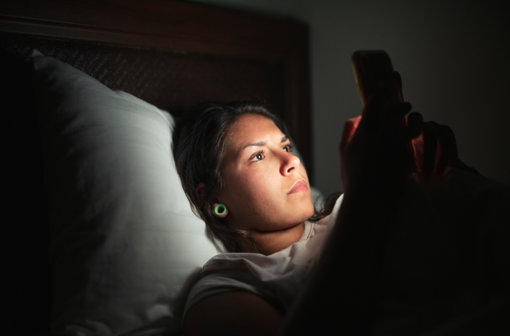 Young woman laying in bed and using smart phone