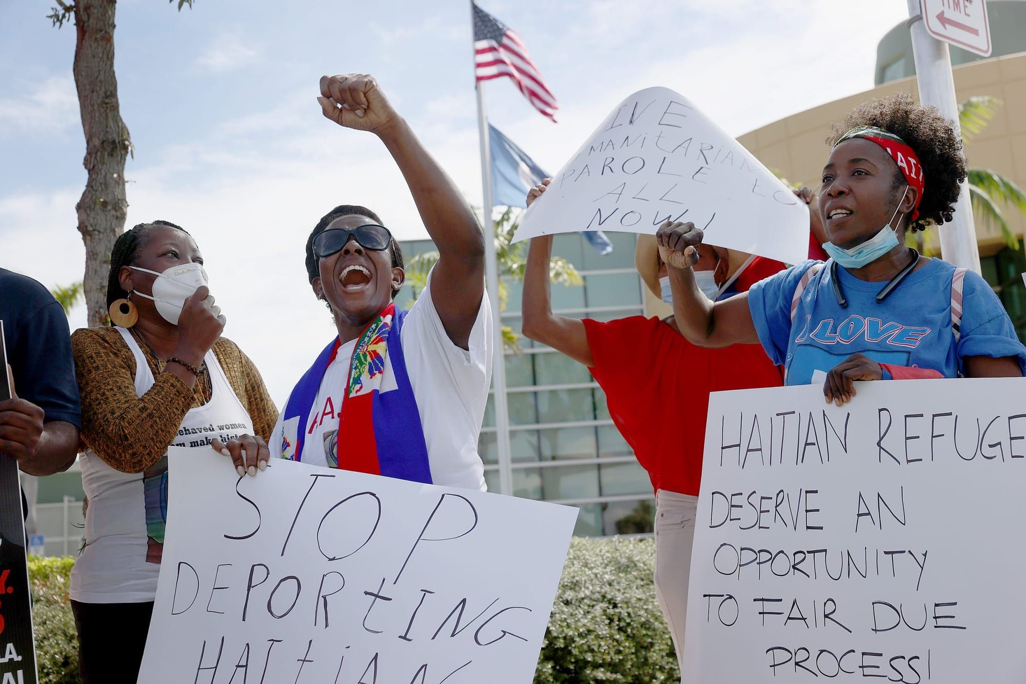 Loverson Tiodatte (C) and Santcha Etienne (R) join other protesters in front of a USCIS Building to denounce the expulsion of