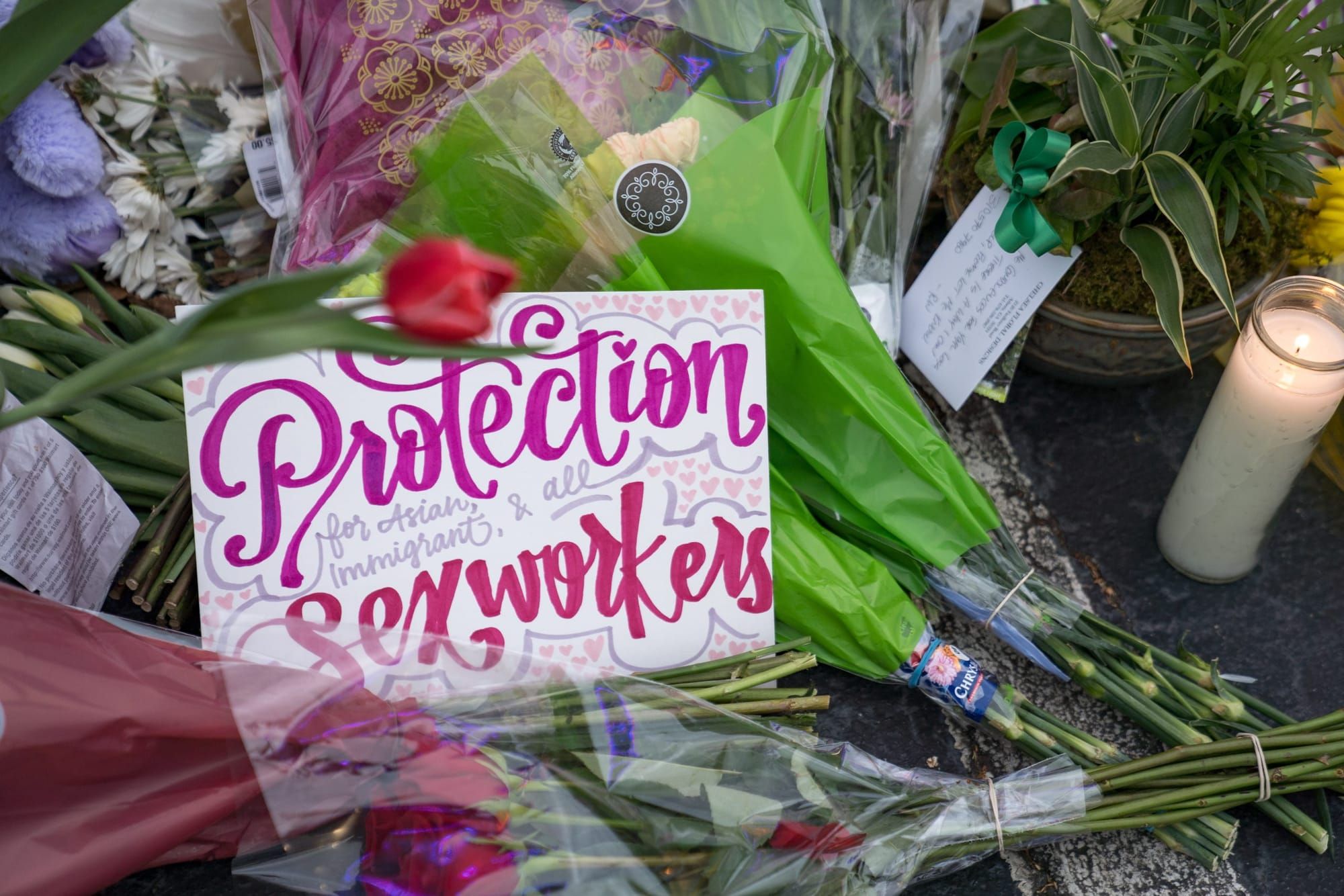 a sign reads "Protection for Asian, immigrant, and all sex workers" in pink ink
