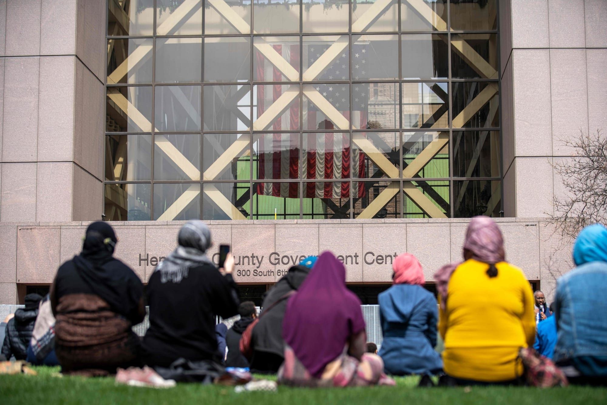 Muslims kneel on grass outside of the Hennepin County Government Center