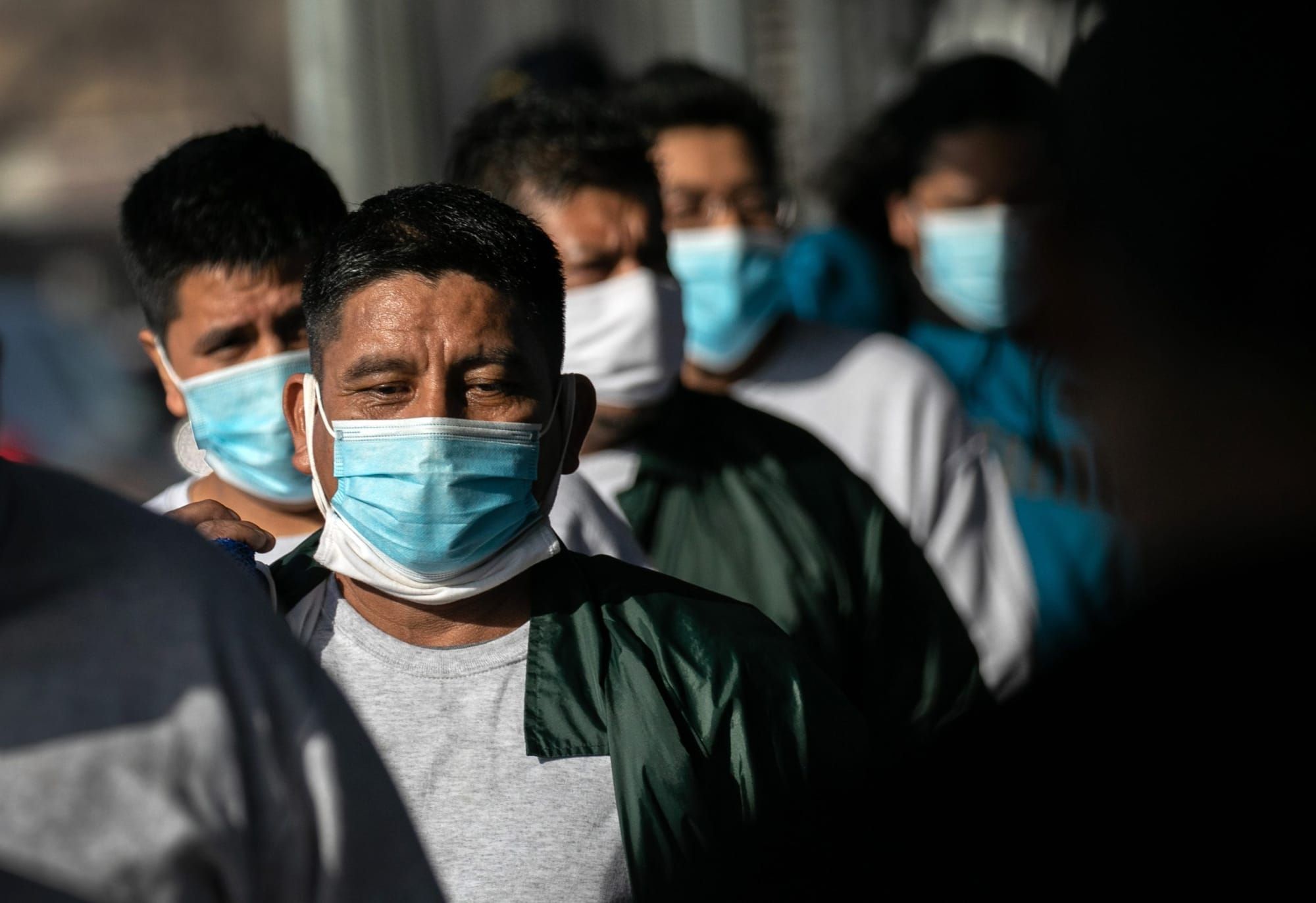 Mexican men stand in a line wearing blue face masks