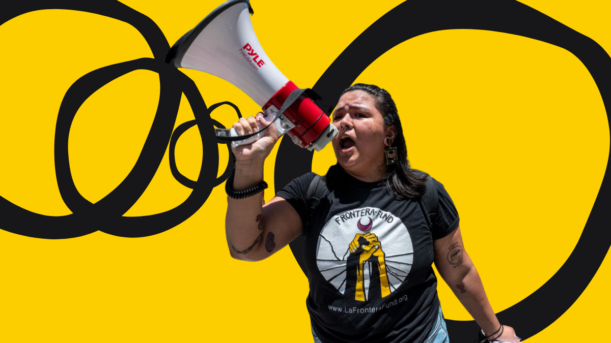 a woman holds up a bullhorn while wearing a black T-shirt with a logo for Frontera Fund on it
