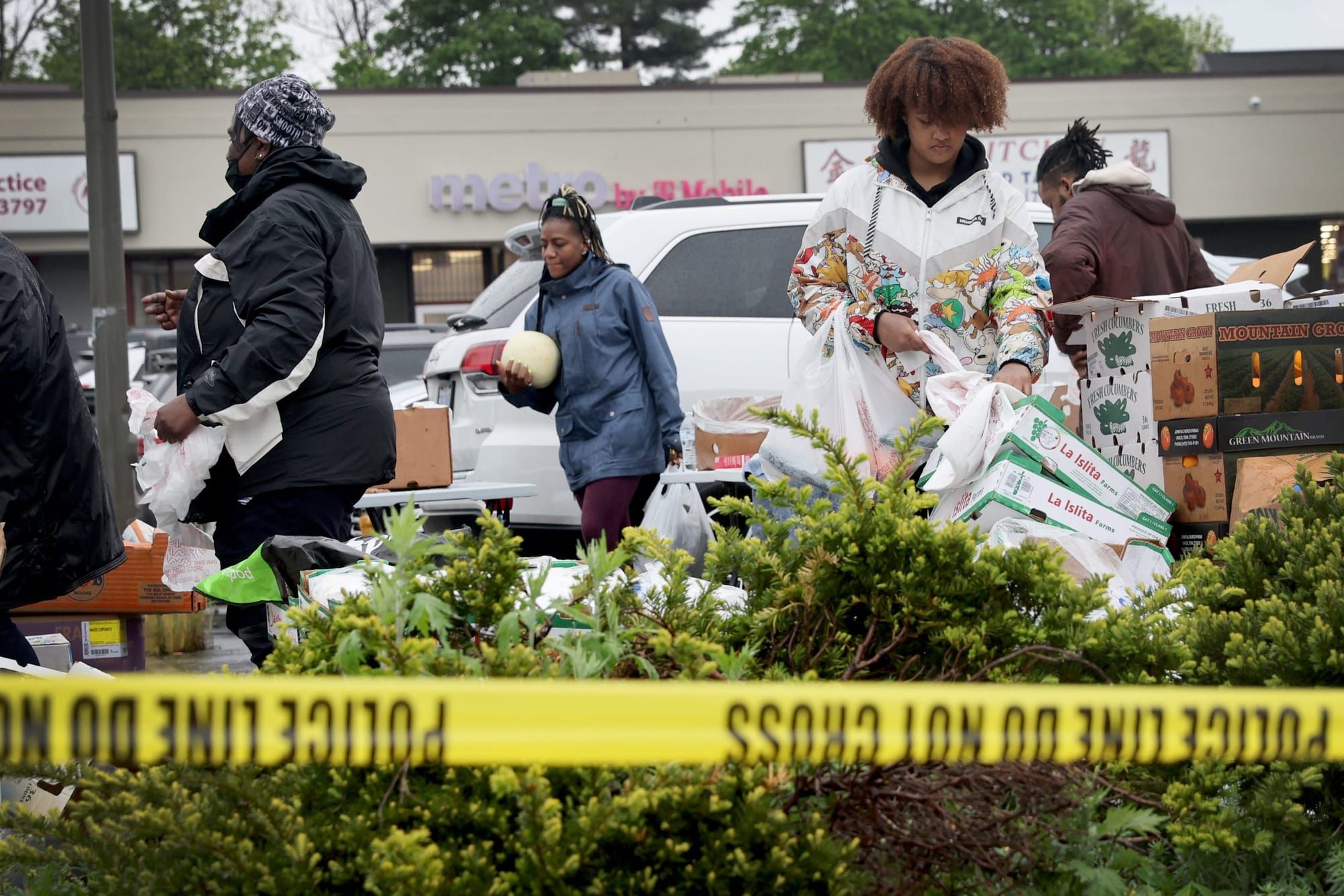 Black people carry fresh produce behind yellow police tape