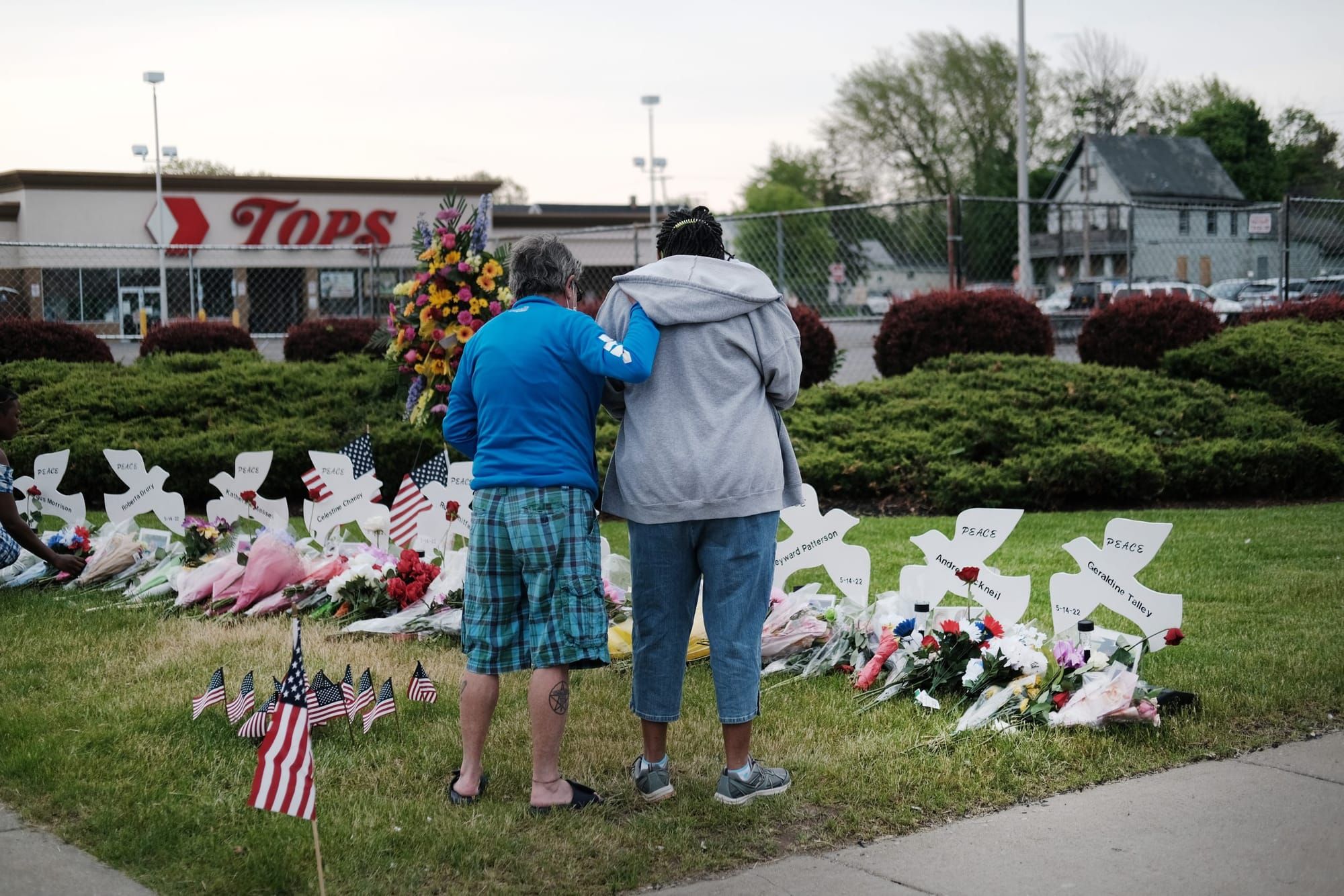 two people stand before a memorial in front of the Tops grocery store in Buffalo