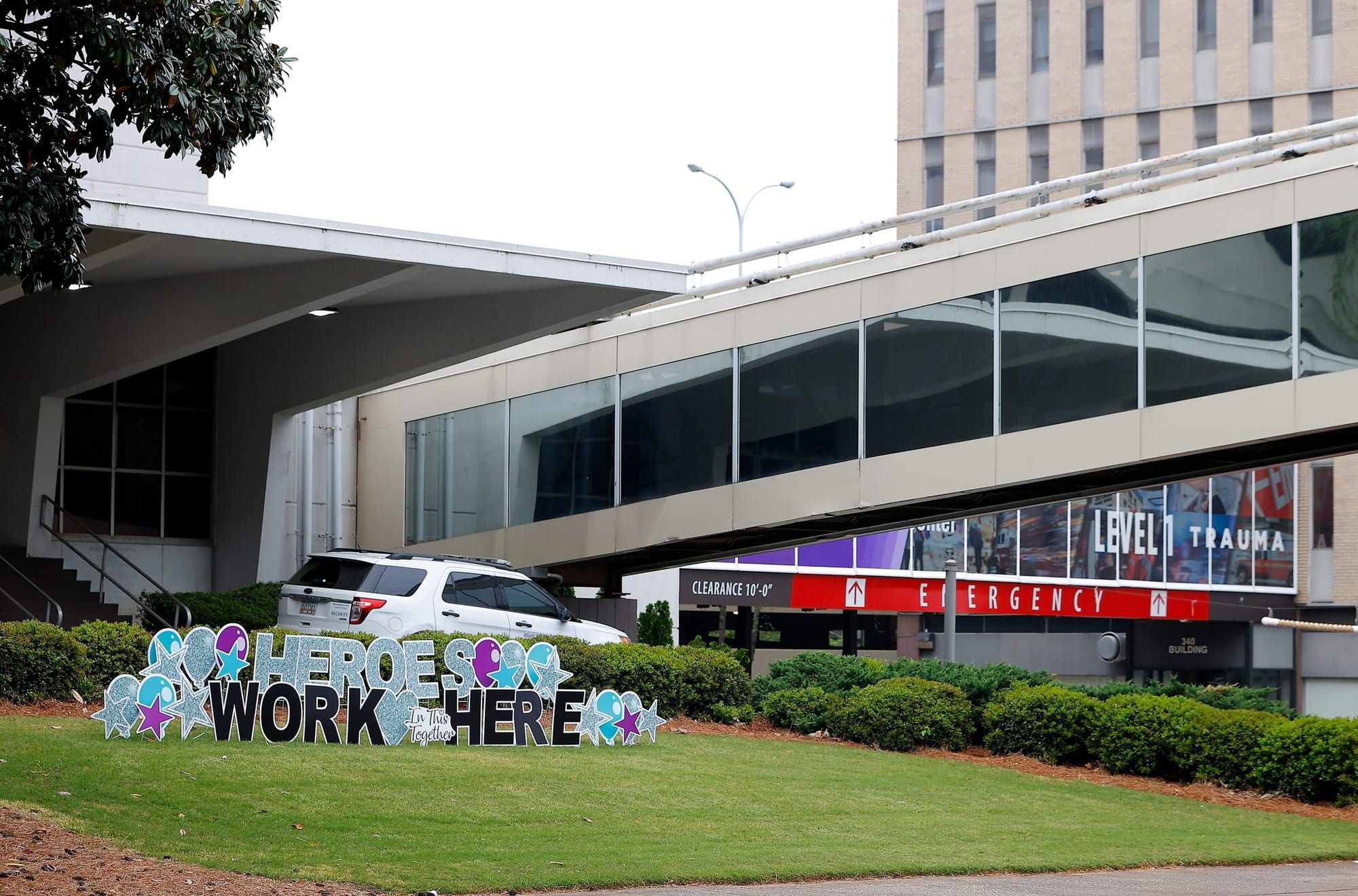 a large sign with cut-out blue and black letters reads "Heroes work here" on a green lawn in front of Atlanta Medical Center