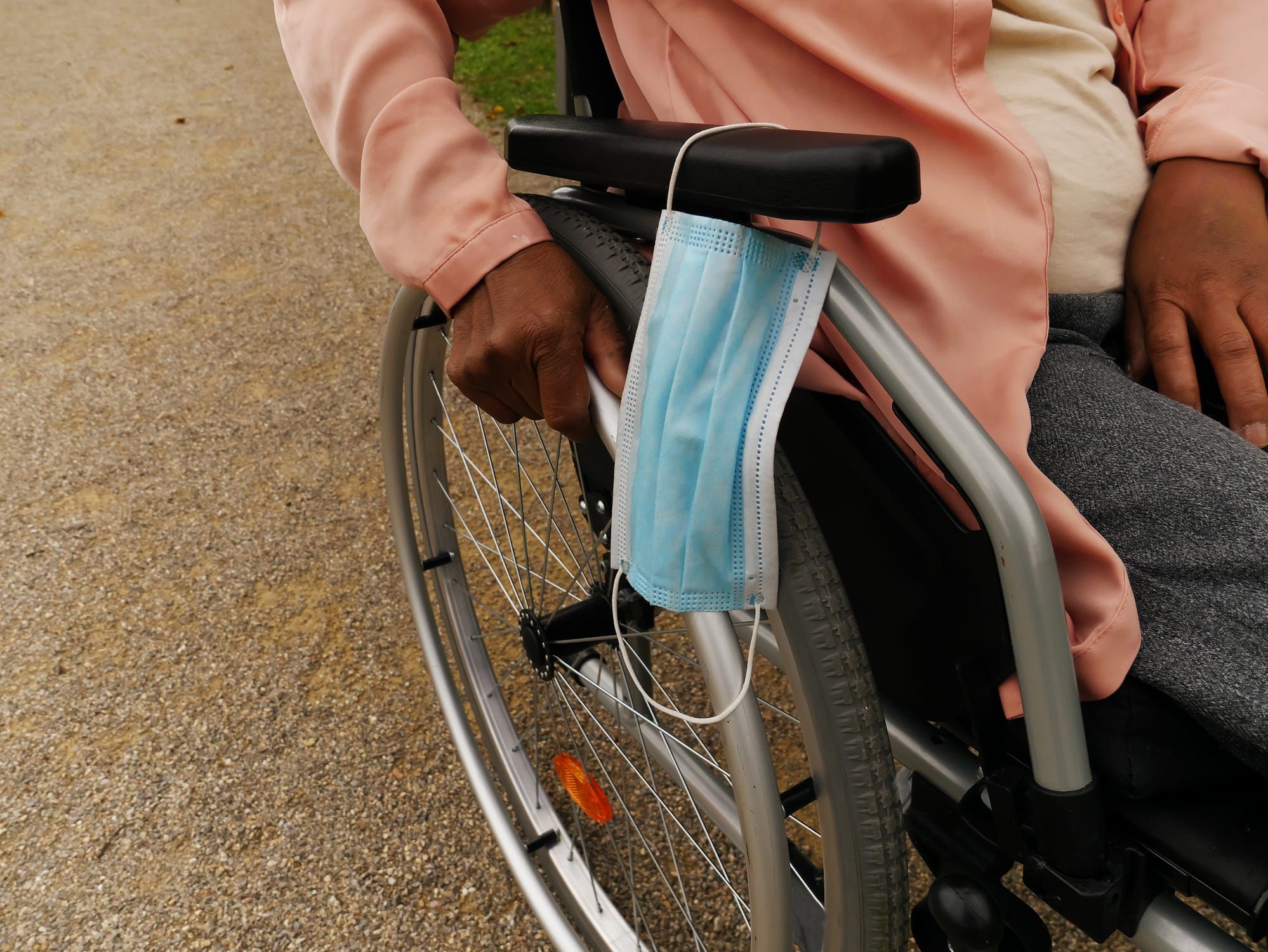 color photograph of a black woman sitting in a wheelchair, taken from a side-front angle. the frame is close, only showing pa