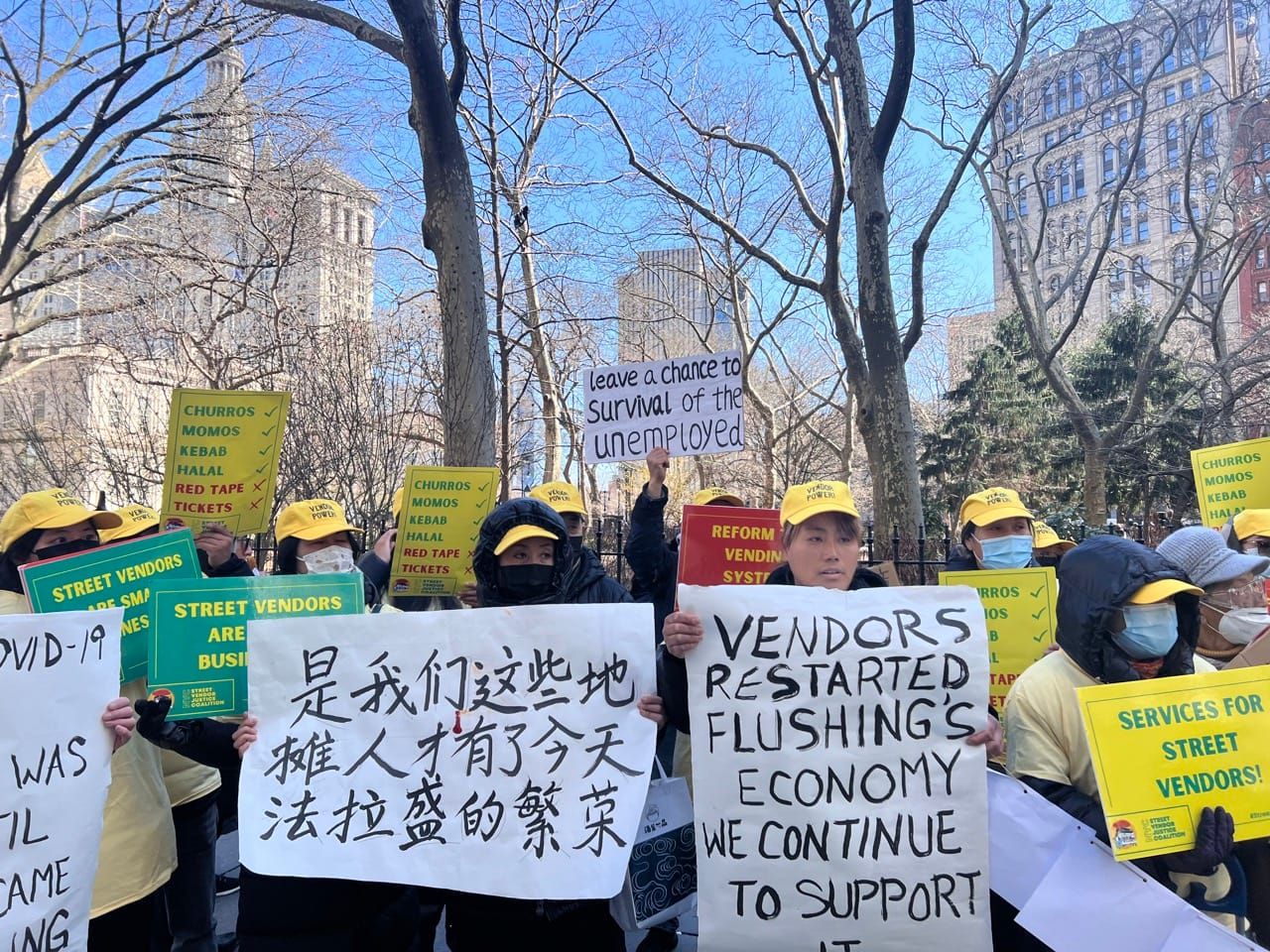 color photo of an outdoor protest where people hold up white and yellow paper signs in chinese and english in support of new