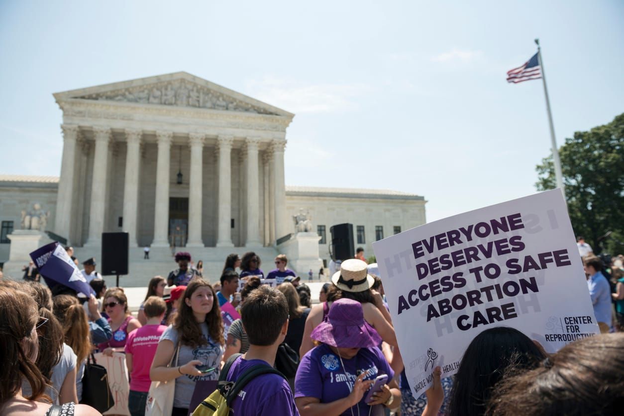 color stock photo of pro-choice protesters standing outside the U.S. Supreme Court. the sky is clear and bright, and someone