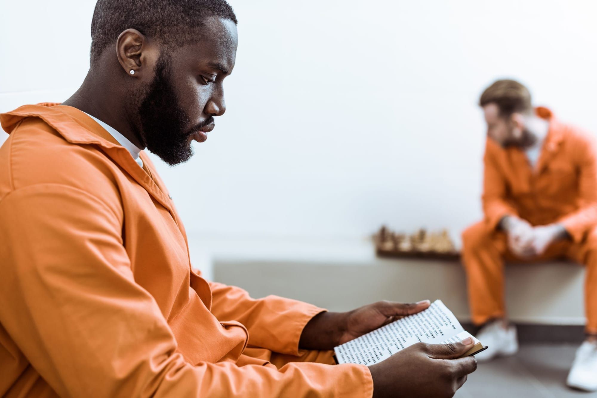 side view of a Black incarcerated person reading book