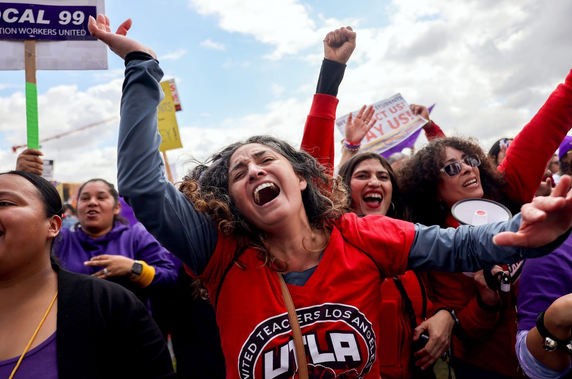 color photograph of an outdoor rally in support of Los Angeles United School District teachers. A woman in a bright red shirt