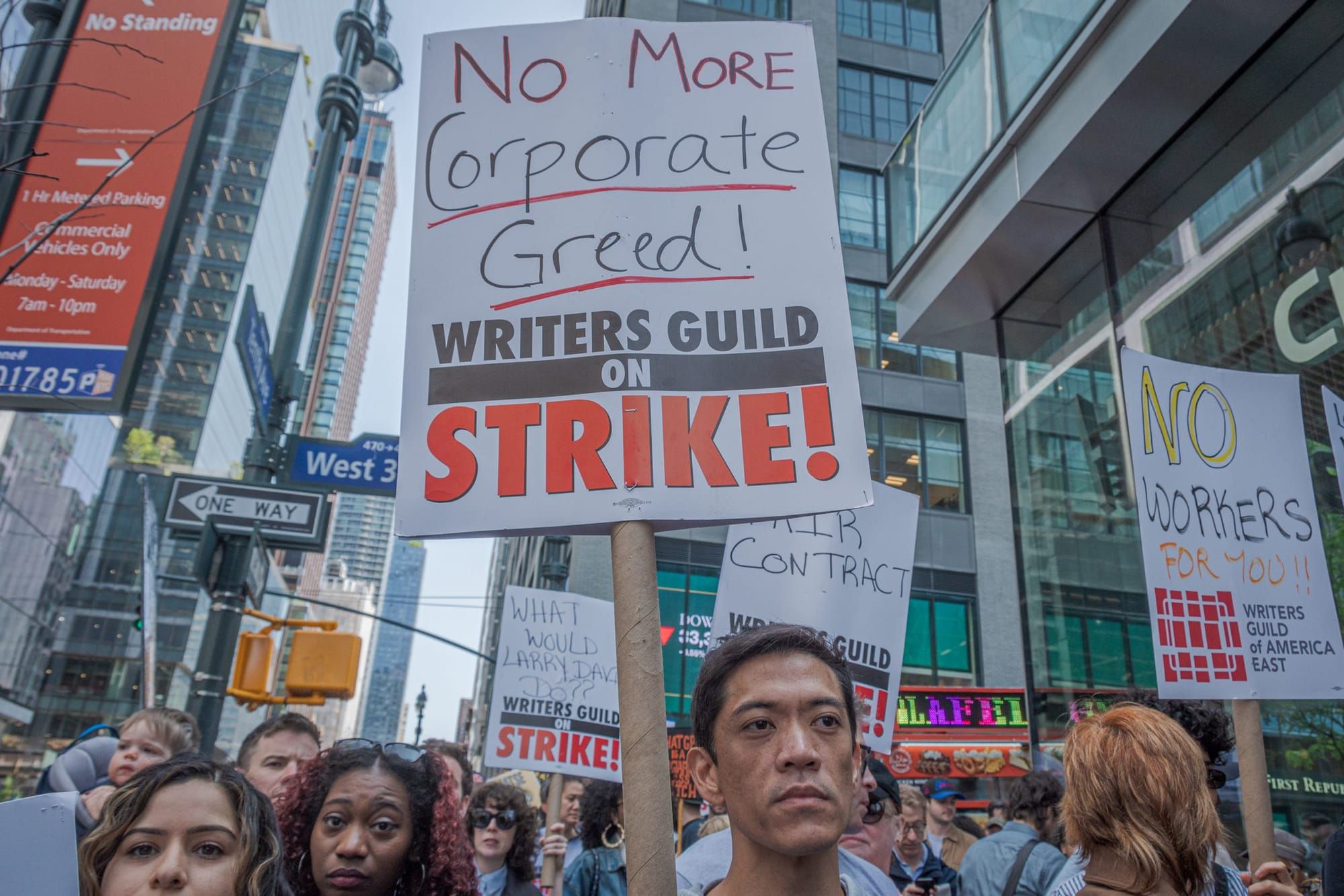 color photograph of an outdoor protest in front of several skyscrapers. the frame cuts off at people's necks and chins to foc