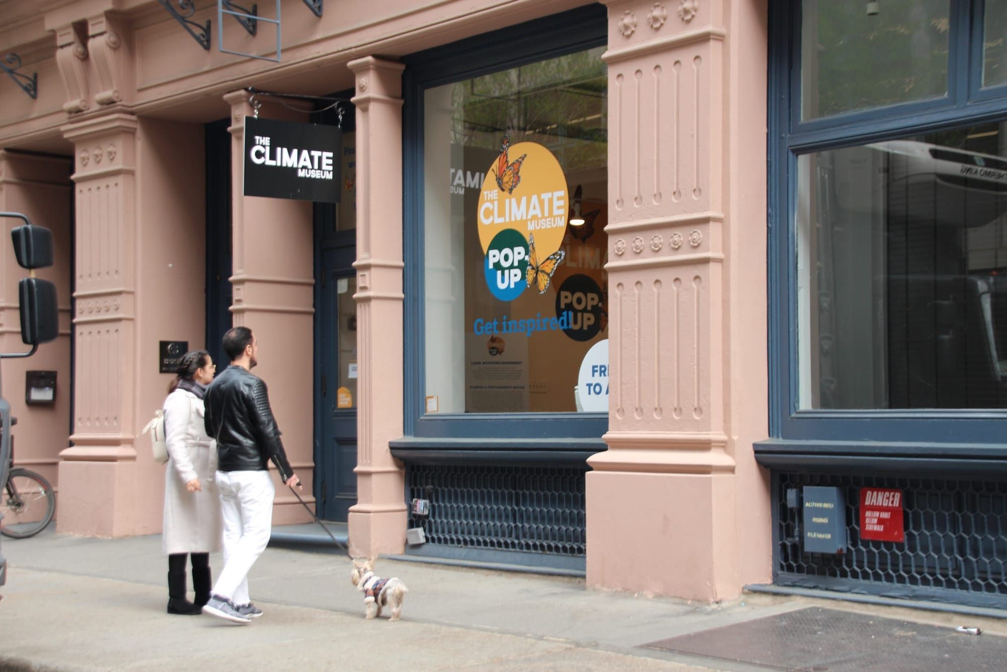 color photograph of the exterior of a row of commercial buildings with brown faux column facades. a black sign hangs above on