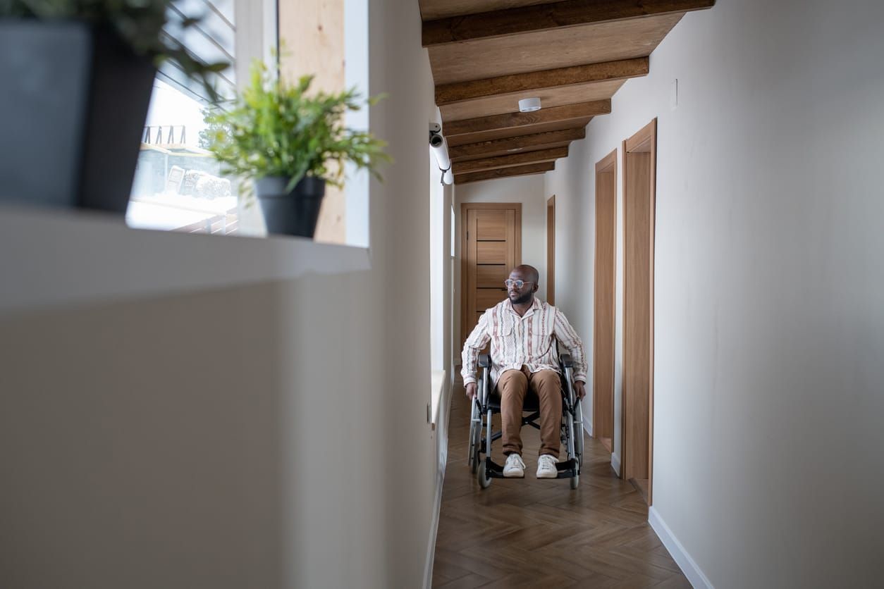 color stock photo of a Black man in a wheelchair wearing brown pants and a white and brown striped button-down. he moves down