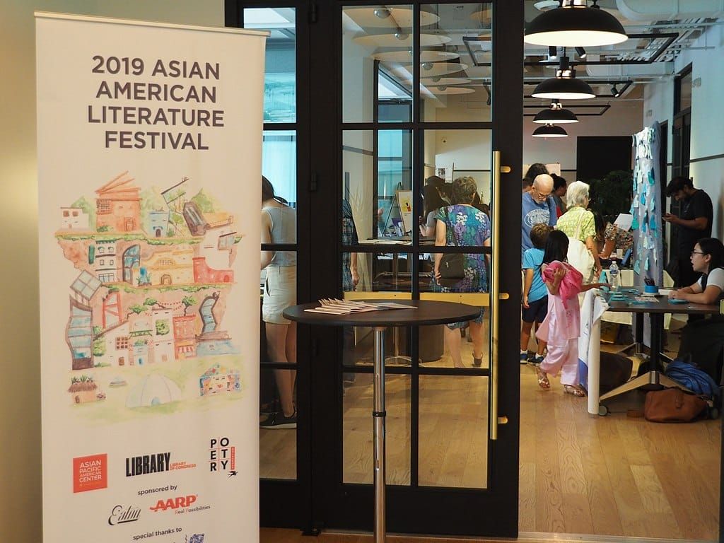 color photograph of a paneled glass door with a large vertical banner sign to the left reading "2019 Asian American Literatur