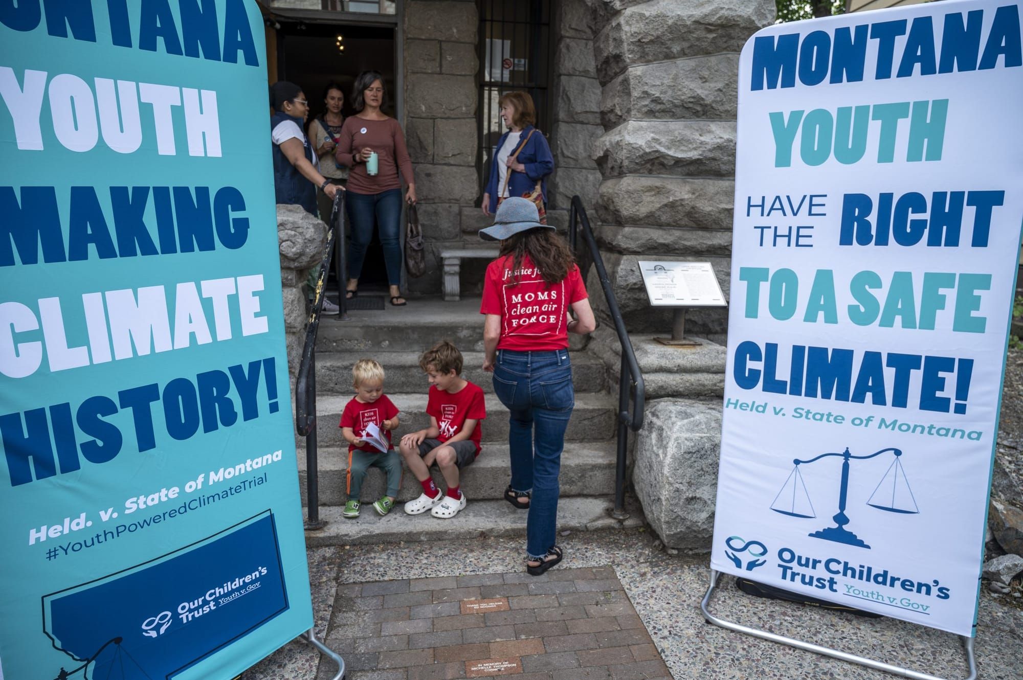 color photograph outside a stone building archway. large signs flank the archway; the left is light blue with alternating dar