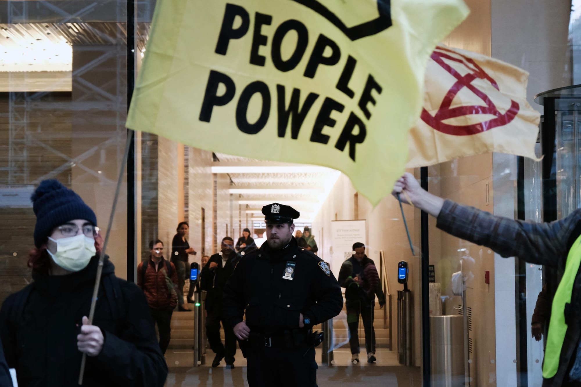 color photograph of people holding flags with "people power" and anarchist symbols printed on them. underneath the flags in t
