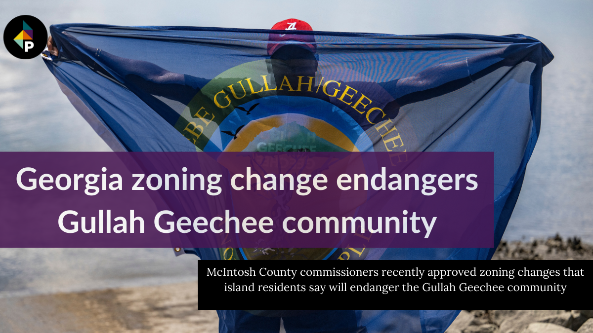 color photograph of a Black man wearing a red baseball cap holding up a blue flag of the Gullah Geechee people