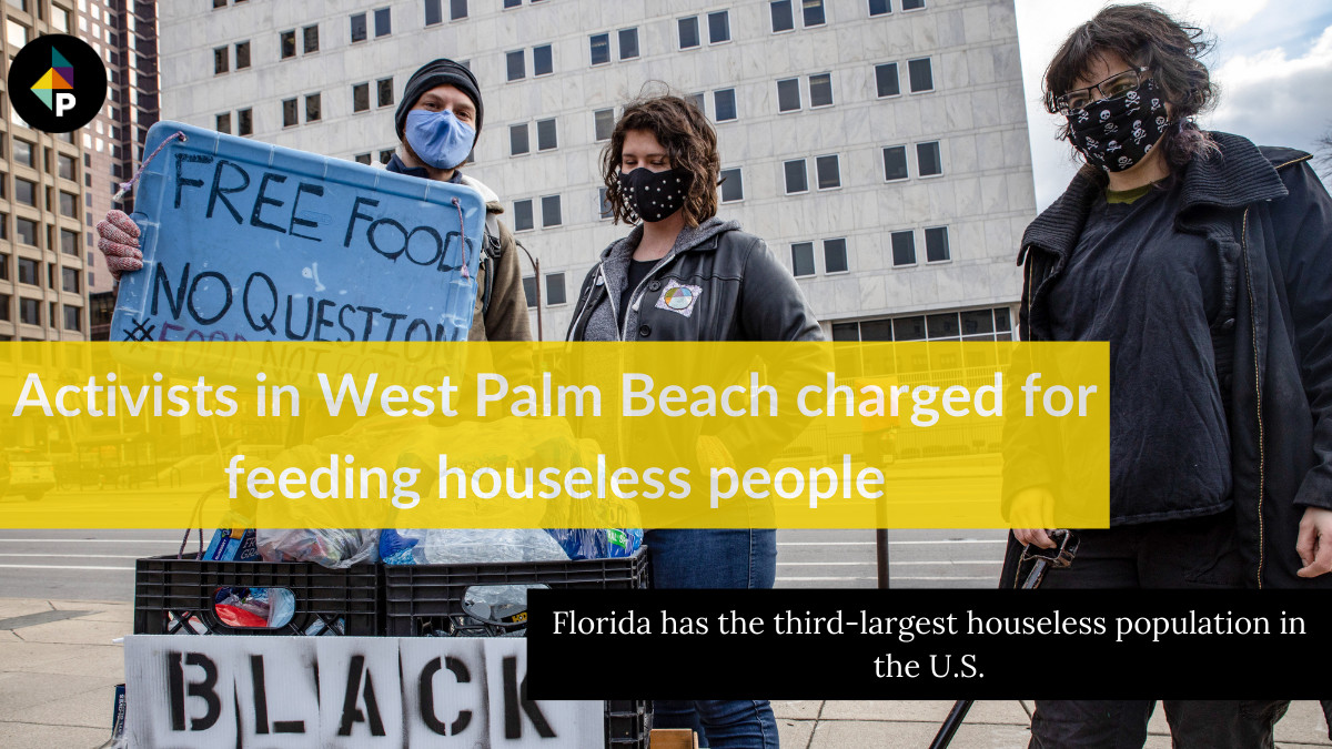 color photograph of three people wearing masks standing on an urban sidewalk. the person on the left holds a blue paper sign