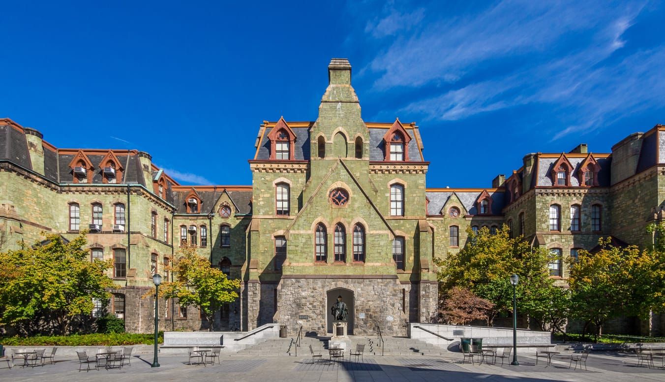 color photograph of the exterior of a stone facade university building against a blue sky