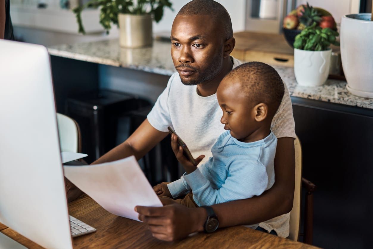 color stock photo of a black man and son working on a computer in their home