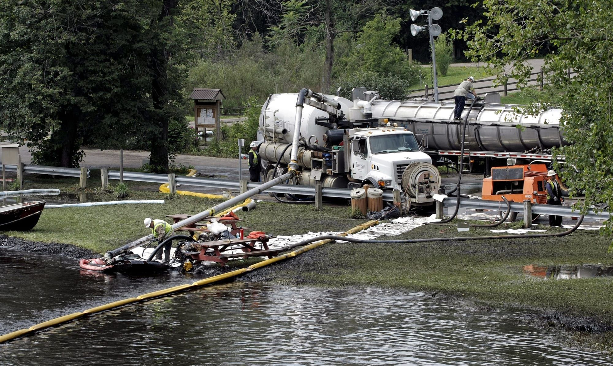 color photograph of an oil spill clean-up crew on the shore of a river